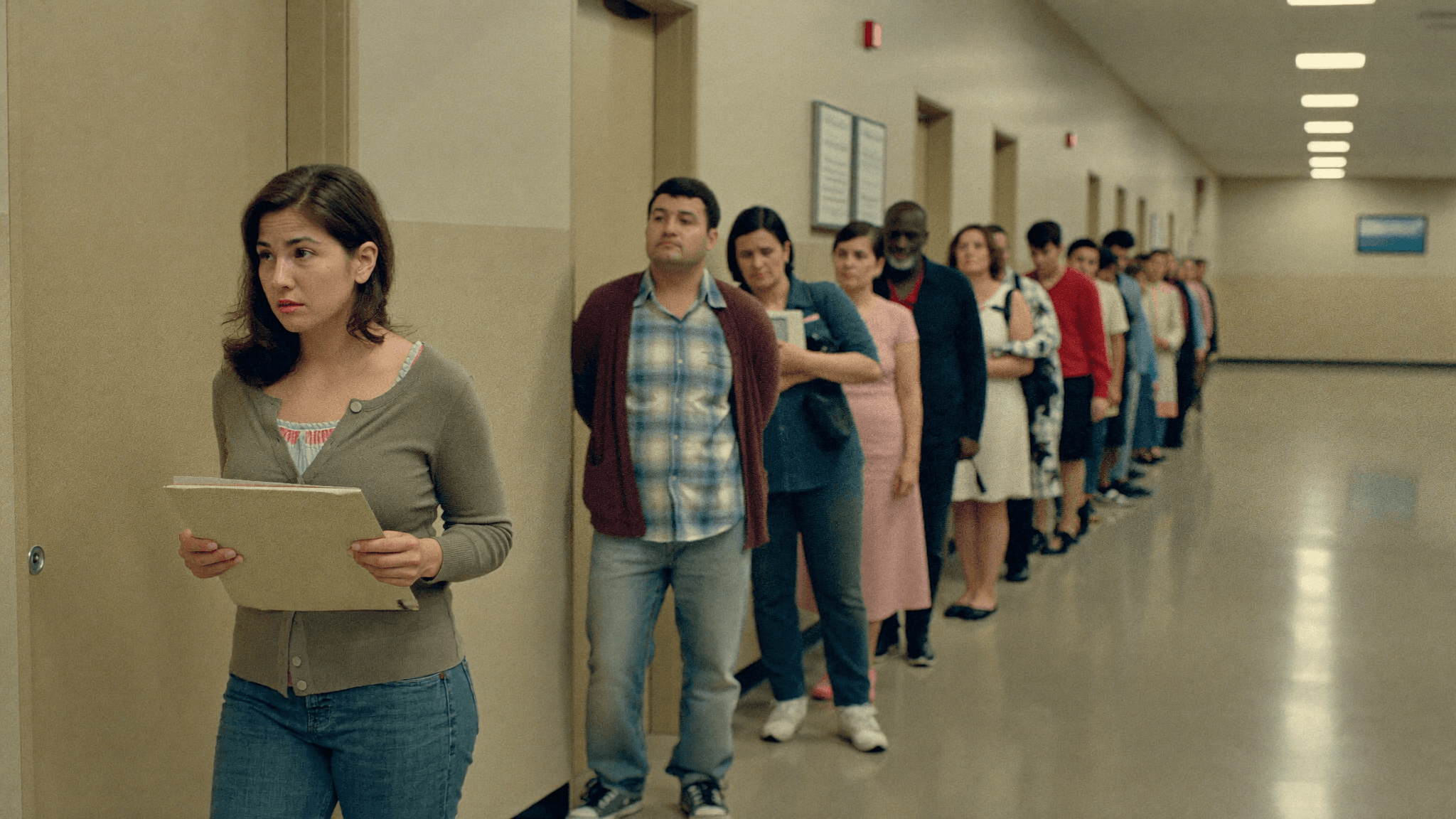 A long line of weary people waiting in a courthouse hallway